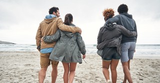 Two young couples walking arm-in-arm on the beach, double date