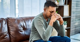 Anxious man praying on his couch