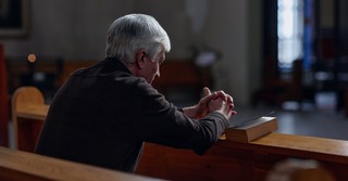 Man praying in a church pew