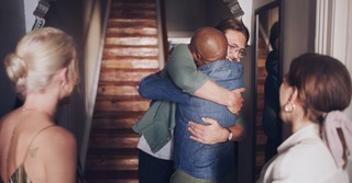 Two men enthusiastically hugging in a doorway