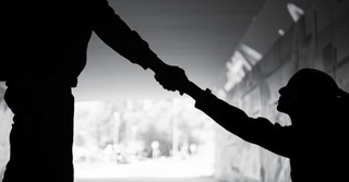 Silhouette of a man reaching a hand down to help a woman