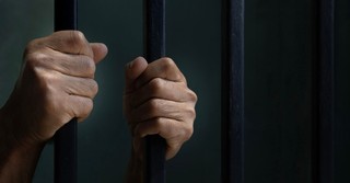 Hands on a jail cell