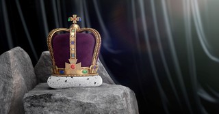 An elaborate purple and gold crown sitting on a rock