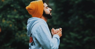 A man praying outside with his hands folded