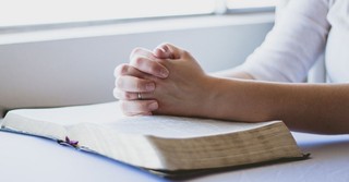 Woman praying over an open Bible