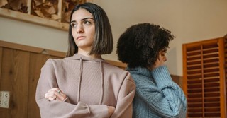 Two women in disagreement, standing back to back