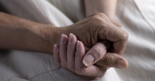 elderly couple holding hands in hospice