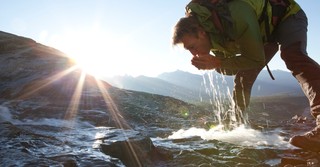 man drinking from a fresh spring in the mountains