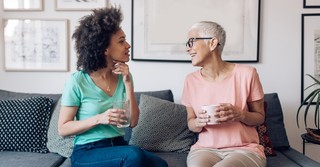 Senior woman talking with adult woman on couch