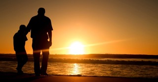 Silhouette of a dad and son on the beach at sunset