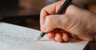 Close up of a man's hand holding a pen, writing a letter