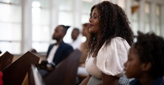 Mom and son sitting at church pew praying