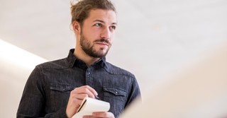 A reporter listening to a source and taking notes