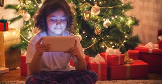 Child playing video games by a Christmas tree