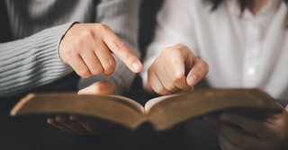 Parent and teen reading Bible study together