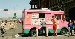 An ice cream truck on a street corner in the summer