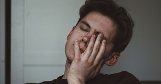 A tired young man with his face in his hands