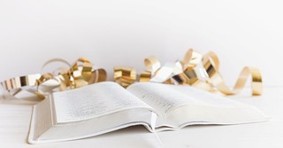 An open Bible with gold New Year's confetti next to it