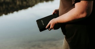 **Alt Text:** A person stands beside a calm body of water holding a Bible, reflecting on faith, Scripture, and personal devotion in a peaceful outdoor setting.