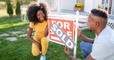 A couple putting up a sold sign, survey reveals that 1/3 of young people in America see property ownership as a bad thing