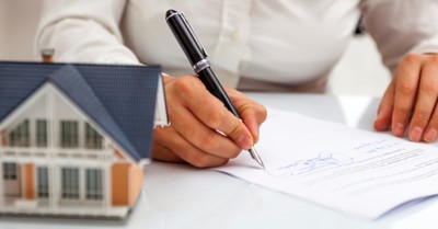 a man signing a contract, Manhattan Christian College to buy a retail center and apartment center to expand college