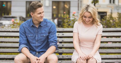 Young man and woman sitting on a park bench