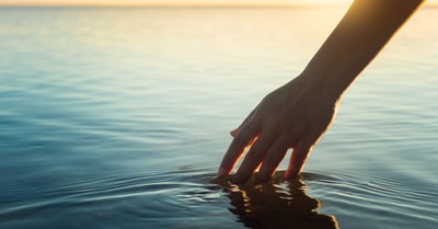 a person's hand in a body of water, An 86-year-old woman overcomes a fear of water and gets baptized