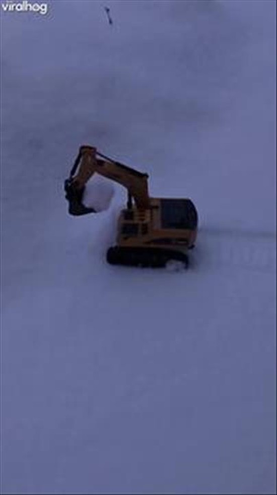 Miniature Excavator Works To Clear Snowfall