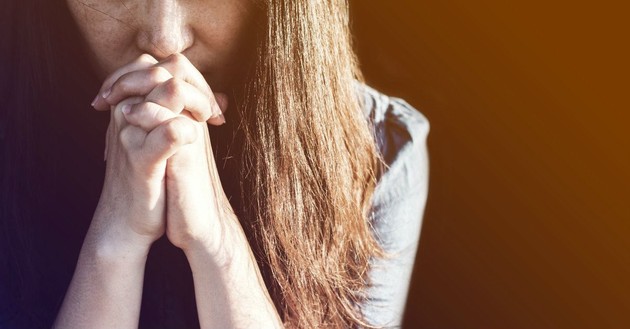 woman with head bowed and handed folded in prayer