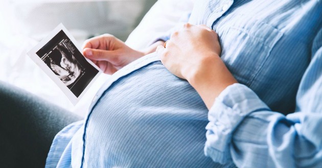 pregnant woman looking at sonogram picture
