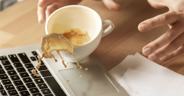 hands trying to grab spilling coffee cup splashing coffee on laptop