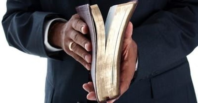 closeup of man's hands holding open Bible