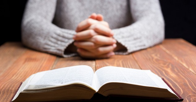 woman folding her hands by the bible