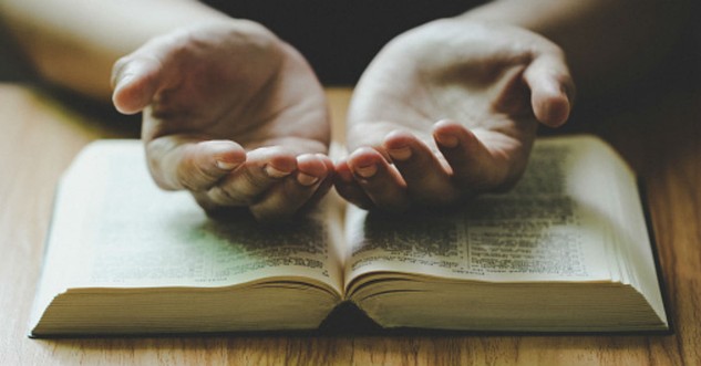 Hands open over a Bible