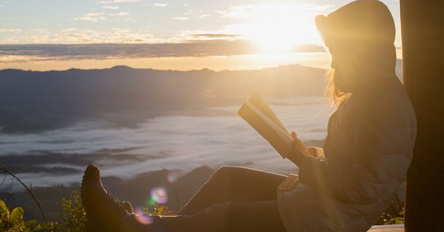 Woman reading the Bible outside at sunrise