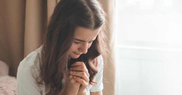 Woman praying beside a window