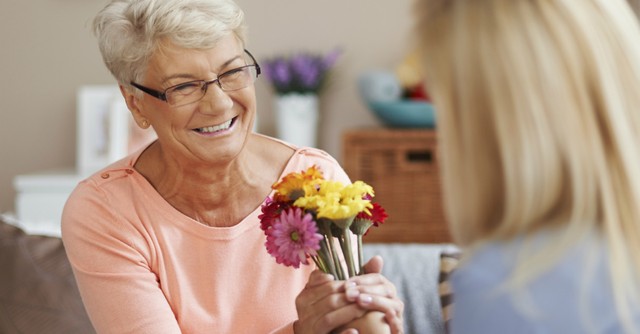 Senior woman accepting the gift of a bouquet of flowers