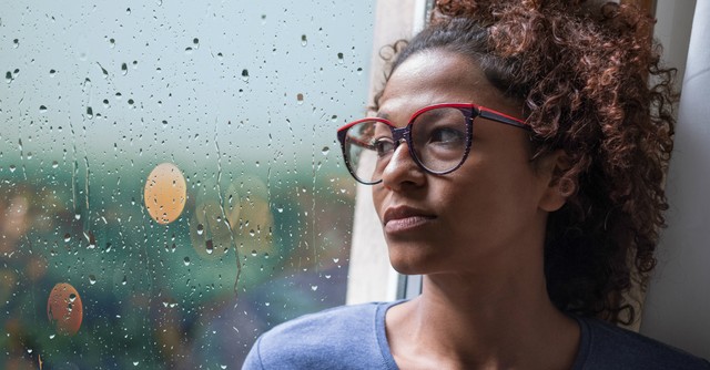 Sad woman looking out a rainy window