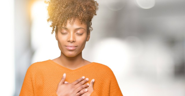woman peaceful eyes closed hands on heart