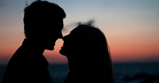 Silhouette of a couple at sunset, about to kiss