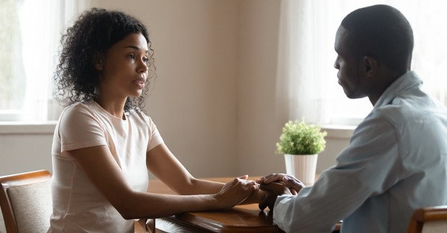 woman and man couple holding hands sitting talking looking serious, how to respond to spouse doubts