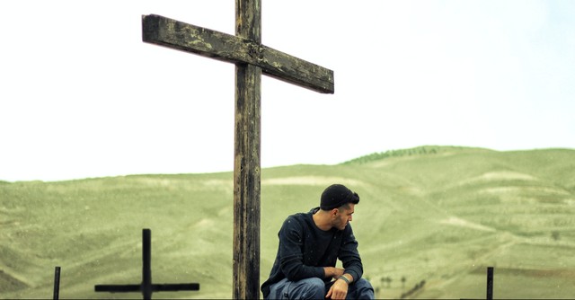 A man sitting at the foot of the cross