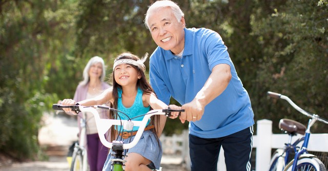 grandparents with grandchild helping her ride a bike