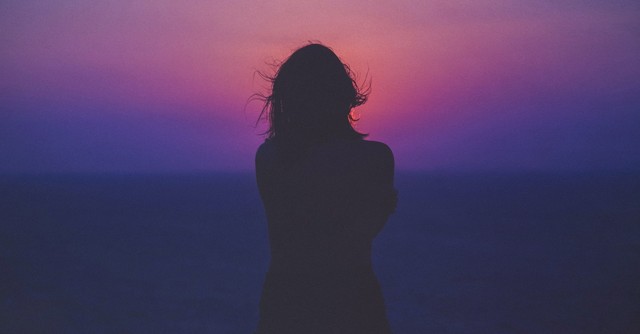 woman silhouette standing in front of ocean sunset sunrise