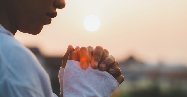 A woman praying at sunset