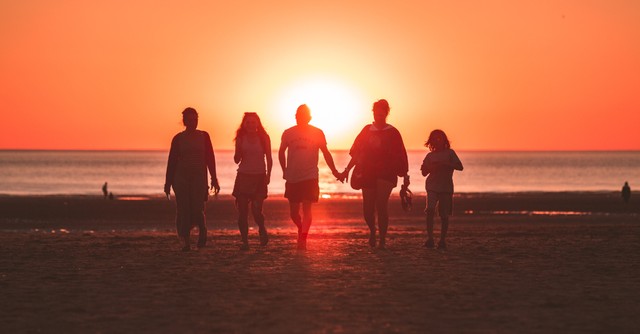family walking on the beach at sunset