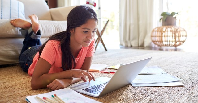 teenage girl working on homework and studying on living room floor, teach teens true definition of success