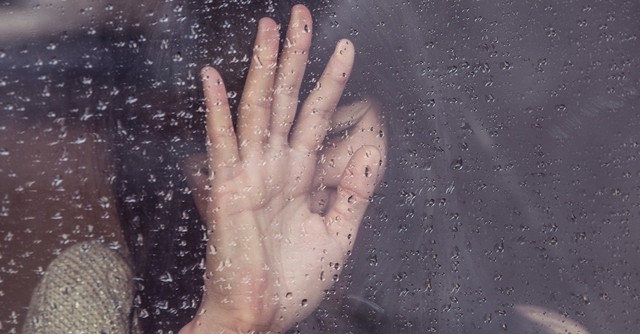 Sad woman with her head up against a rainy window