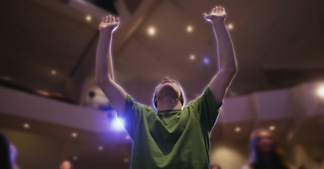 man in church arms up in prayer and praise