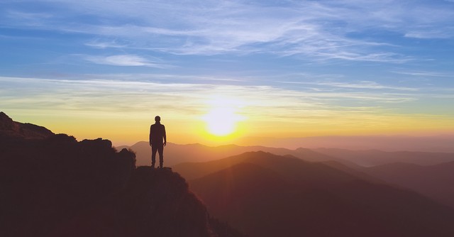 man gazing at sunset on mountaintop